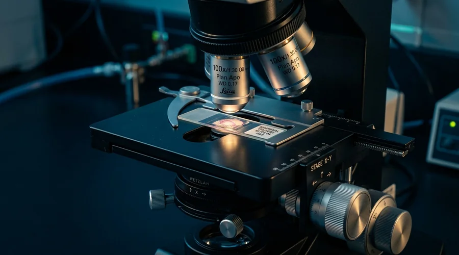 capsule suspension agrochemical process diagram — optical microscope with a slide of microcapsules on a dark bench | Global Formulation