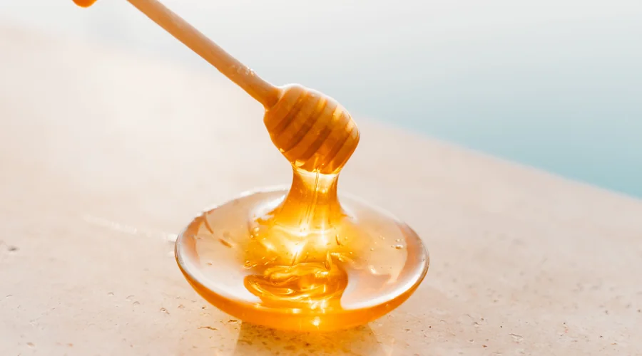 chain lubricant tackiness — tackified bar oil drawing a filament between a glass rod and a beaker on a dark laboratory bench | Global Formulation
